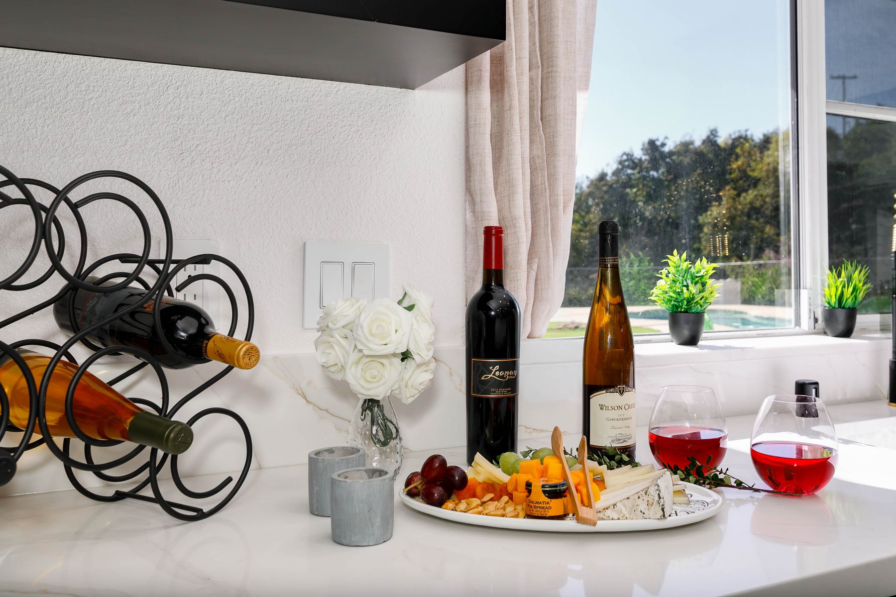 Wine and cheese board staged on kitchen counter overlooking the pool