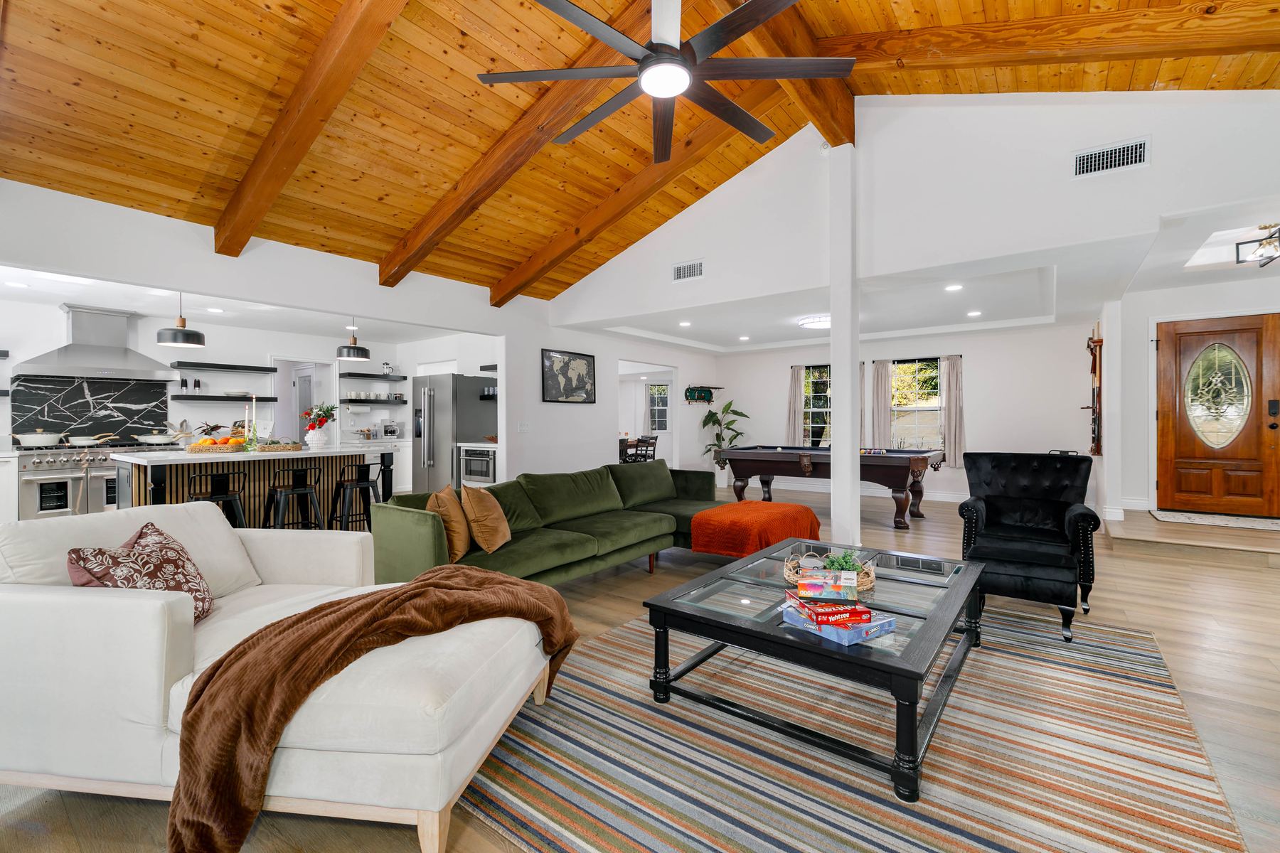 Open-concept living room and kitchen with vaulted wood-beam ceiling